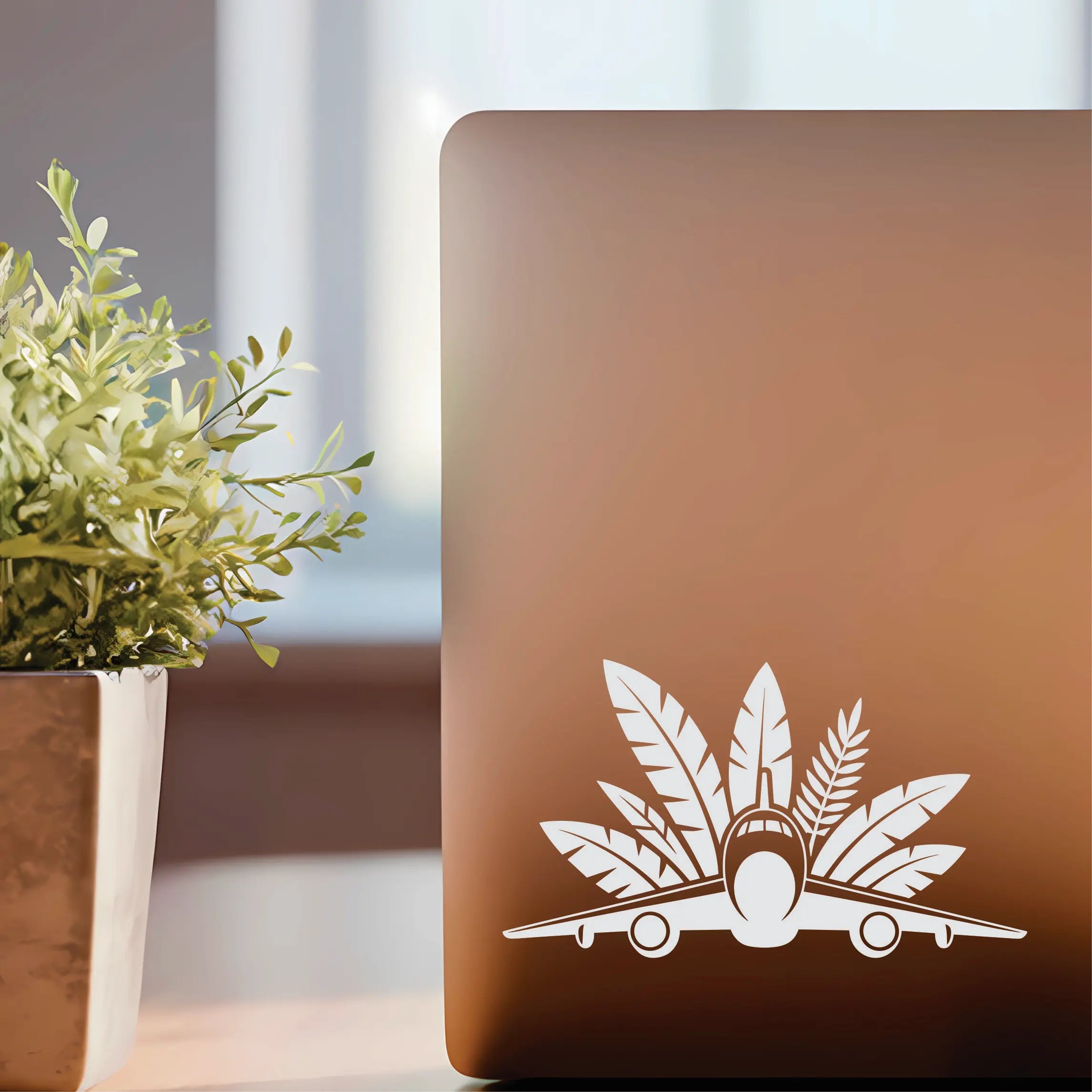 Front-view airplane vinyl decal with lush tropical leaves behind, a clean aviation sticker for pilot cars, crew laptops and travel suitcases.